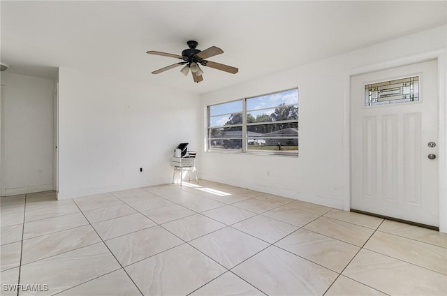 empty room featuring light tile patterned floors, baseboards, and a ceiling fan