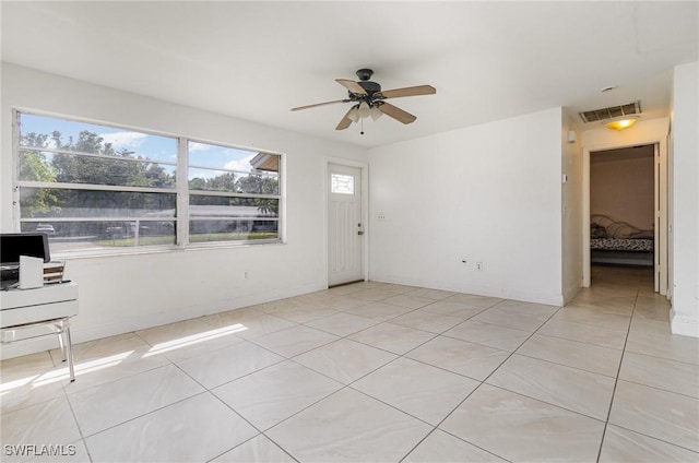 empty room with a ceiling fan, visible vents, baseboards, and light tile patterned flooring