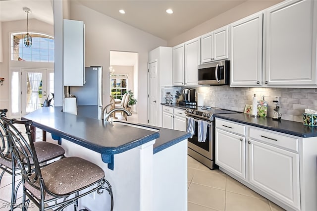 kitchen featuring white cabinetry, stainless steel appliances, light tile patterned flooring, and vaulted ceiling