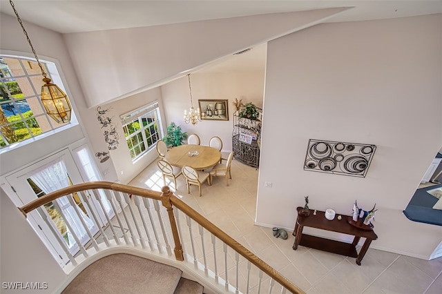 stairway featuring a notable chandelier, tile patterned floors, and high vaulted ceiling