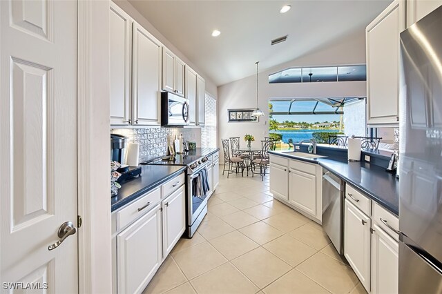 kitchen featuring white cabinetry, stainless steel appliances, hanging light fixtures, and light tile patterned floors