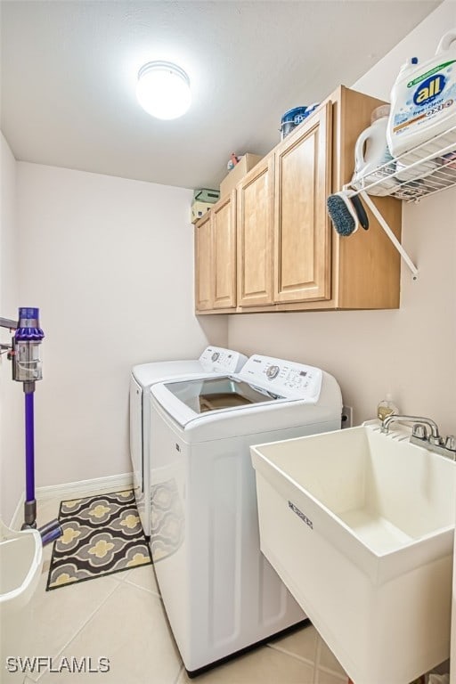 clothes washing area featuring cabinets, washer and clothes dryer, sink, and light tile patterned floors