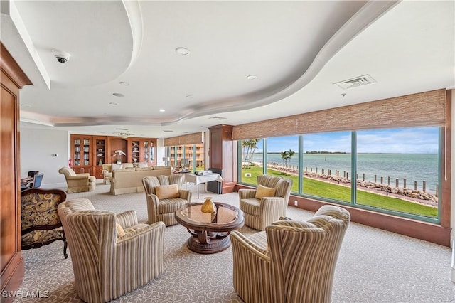 interior space featuring carpet floors, a raised ceiling, and a water view