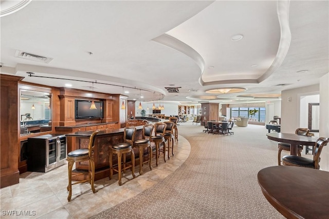 bar with light carpet, track lighting, and a raised ceiling