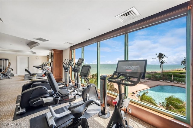 gym with carpet flooring, floor to ceiling windows, and a water view