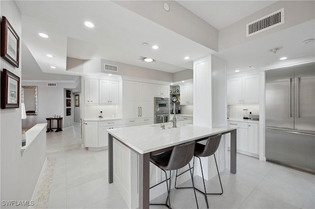 kitchen with white cabinetry, appliances with stainless steel finishes, a kitchen island with sink, and a kitchen breakfast bar