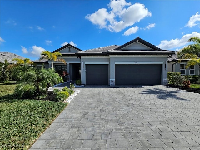 view of front facade with a garage, decorative driveway, and stucco siding