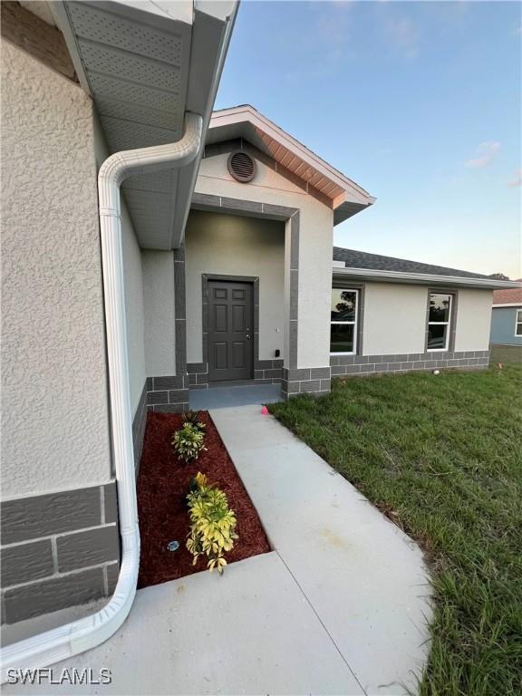 view of exterior entry featuring a yard