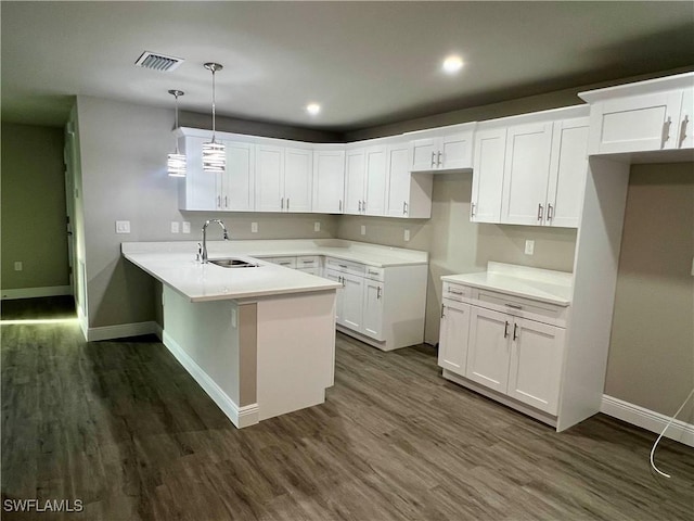 kitchen featuring pendant lighting, sink, dark wood-type flooring, white cabinets, and kitchen peninsula