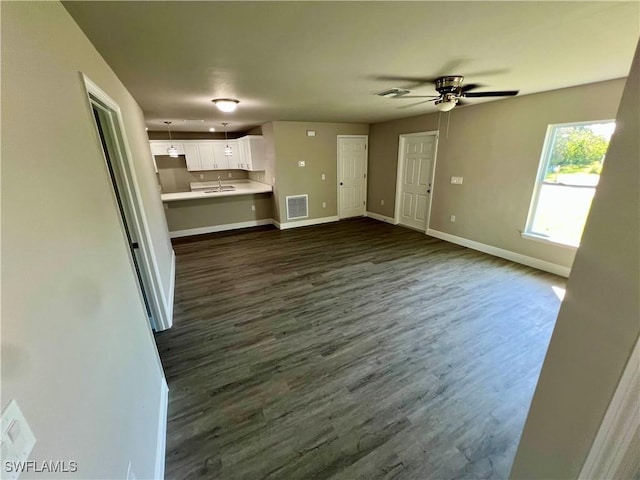 unfurnished living room featuring ceiling fan, dark hardwood / wood-style floors, and sink