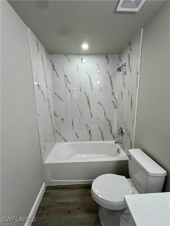 full bathroom featuring tiled shower / bath combo, wood-type flooring, vanity, and toilet