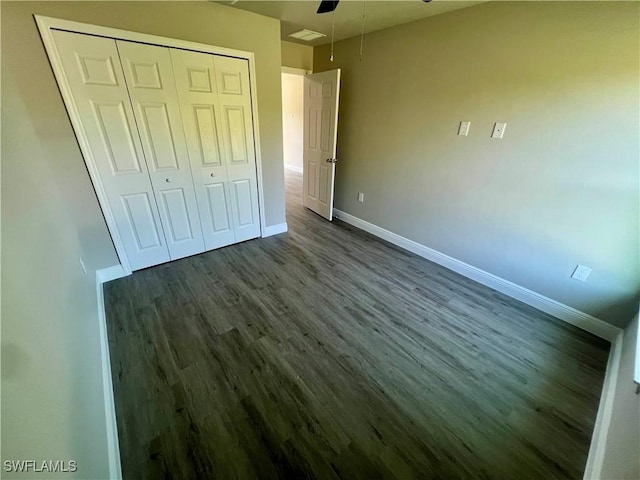 unfurnished bedroom featuring ceiling fan, dark hardwood / wood-style floors, and a closet