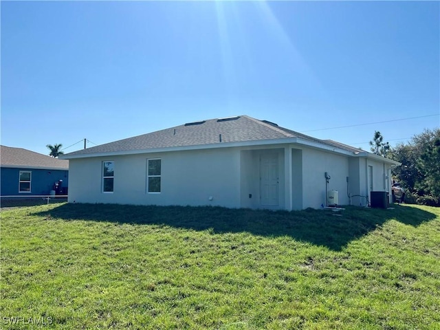 back of house featuring a yard and central AC