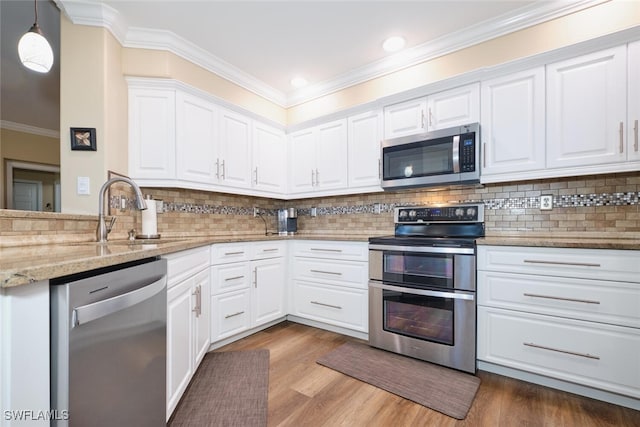 kitchen with stainless steel appliances, white cabinetry, hanging light fixtures, and light stone countertops