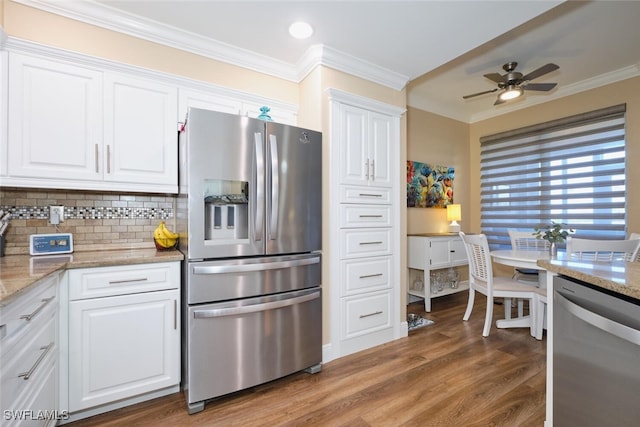 kitchen featuring wood-type flooring, white cabinets, stainless steel appliances, crown molding, and light stone countertops