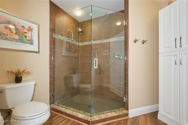 bathroom featuring walk in shower, hardwood / wood-style floors, and toilet