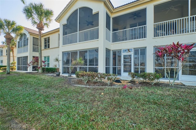 back of property with ceiling fan and a lawn