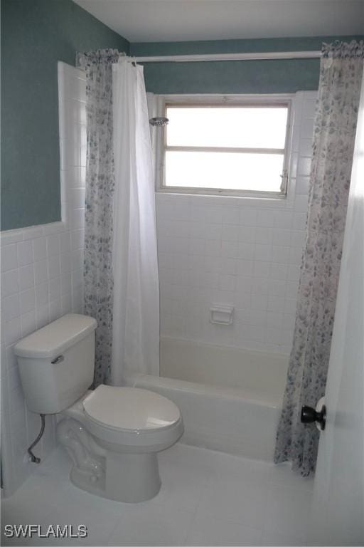 bathroom with toilet, shower / bath combination with curtain, tile patterned flooring, and tile walls