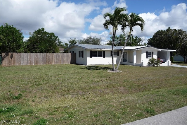 view of front facade featuring metal roof, fence, a front lawn, and stucco siding