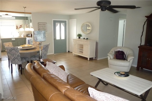 living room with light tile patterned floors, baseboards, a ceiling fan, and a healthy amount of sunlight