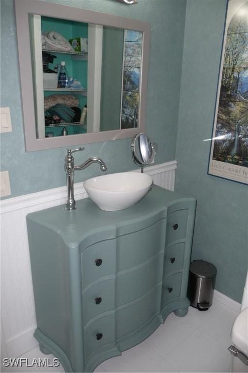 half bath featuring wainscoting, tile patterned flooring, and vanity