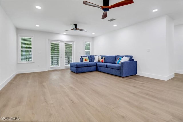 living room with ceiling fan, plenty of natural light, light wood-type flooring, and french doors