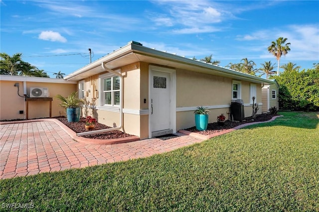 view of side of property with ac unit, a yard, and stucco siding