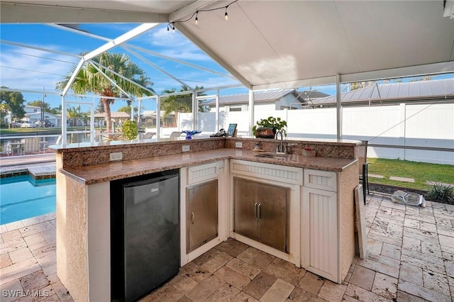 view of patio / terrace with a sink, fence, a fenced in pool, and a lanai