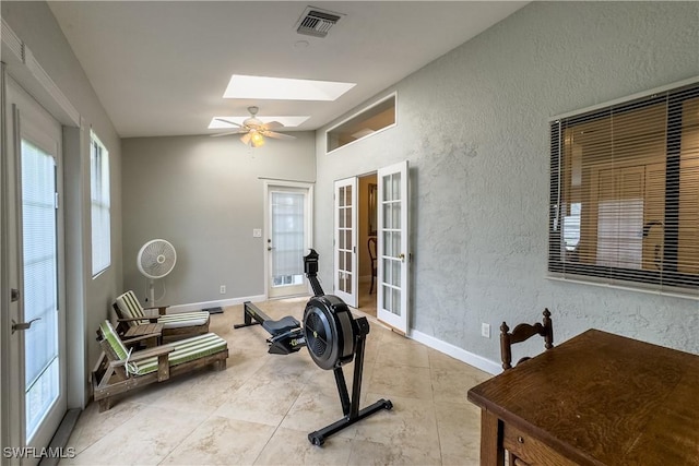 exercise area featuring a skylight, ceiling fan, and french doors