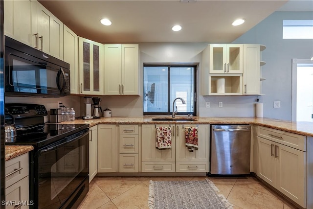 kitchen with open shelves, glass insert cabinets, a sink, light stone countertops, and black appliances