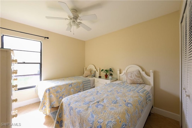 tiled bedroom with ceiling fan and a closet