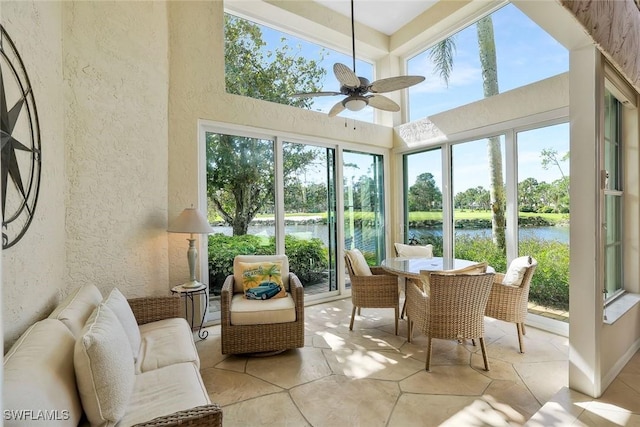 sunroom with a water view, a wealth of natural light, and a ceiling fan