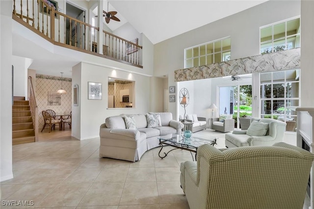 tiled living room with a towering ceiling, ceiling fan, and stairway