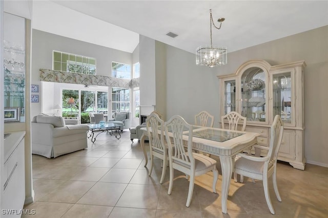 dining area with light tile patterned floors, a high ceiling, visible vents, baseboards, and an inviting chandelier