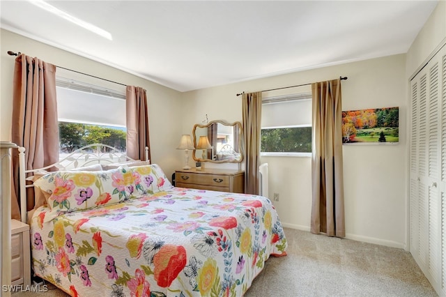 bedroom with multiple windows, light carpet, and a closet