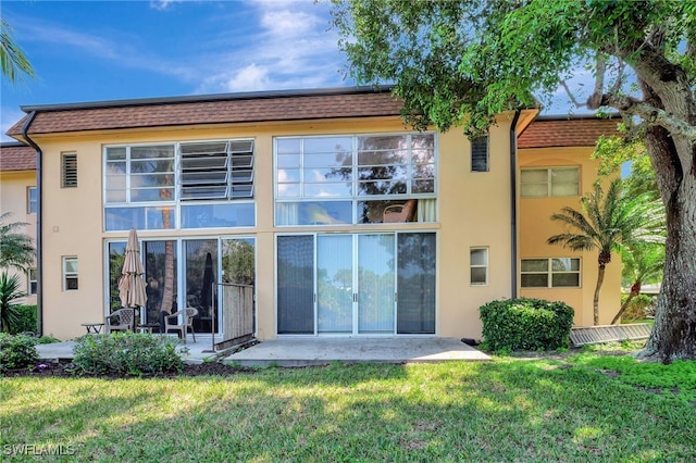 back of property featuring a patio area and a lawn