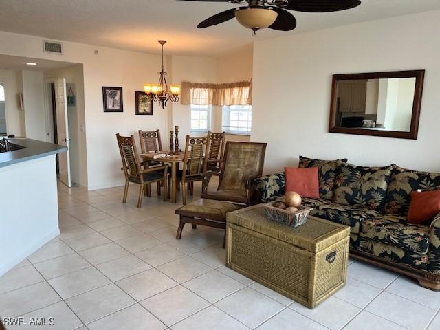 living room with light tile patterned flooring and ceiling fan with notable chandelier