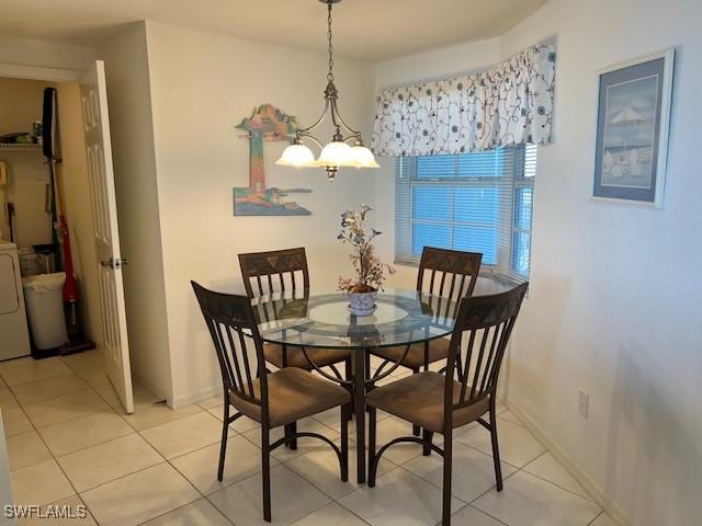 dining space with washer / dryer, light tile patterned floors, and an inviting chandelier