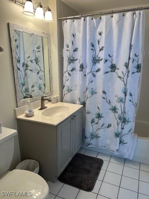 full bathroom with shower / bathtub combination with curtain, vanity, tile patterned floors, and toilet