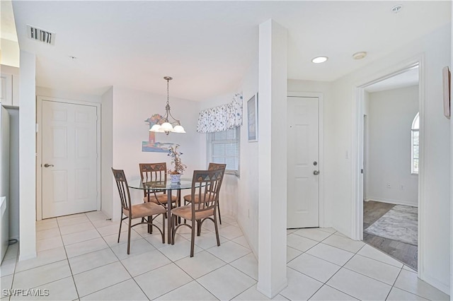 dining space featuring light tile patterned flooring and a notable chandelier