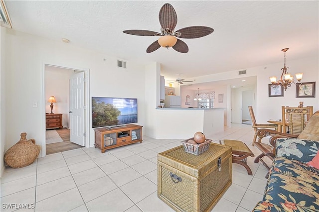 living room featuring light tile patterned floors, ceiling fan with notable chandelier, and a textured ceiling