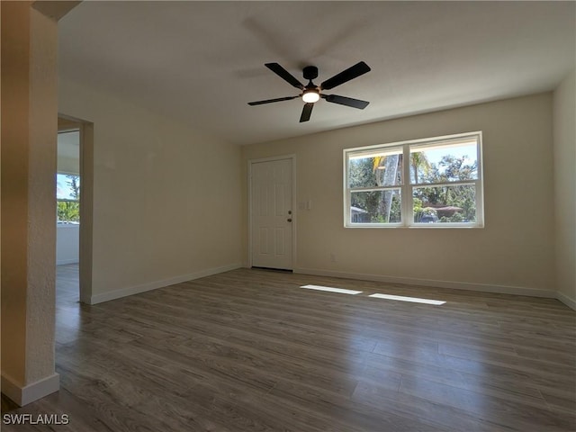 unfurnished room with ceiling fan, dark wood-type flooring, and a healthy amount of sunlight