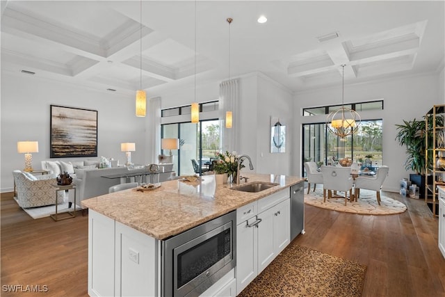 kitchen with stainless steel appliances, light stone counters, a sink, and dark wood finished floors