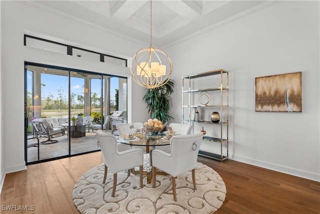 dining room featuring baseboards, wood finished floors, a towering ceiling, and an inviting chandelier