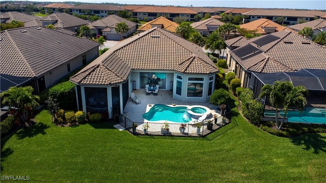 view of swimming pool featuring a patio area, a pool with connected hot tub, a residential view, and a yard