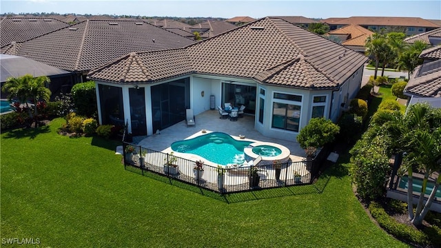 rear view of house featuring a patio, a sunroom, a tiled roof, fence, and a yard