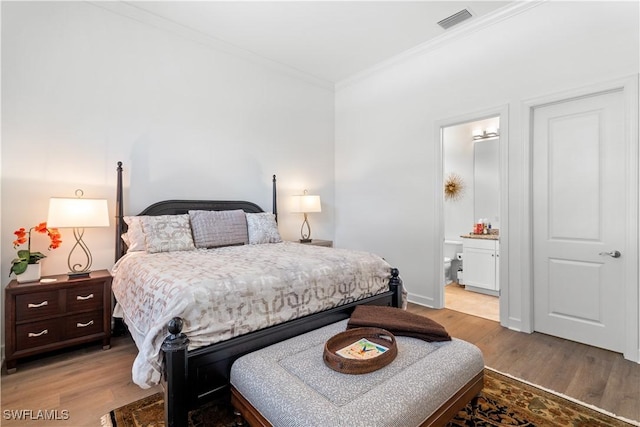 bedroom with light wood finished floors, visible vents, crown molding, and ensuite bathroom