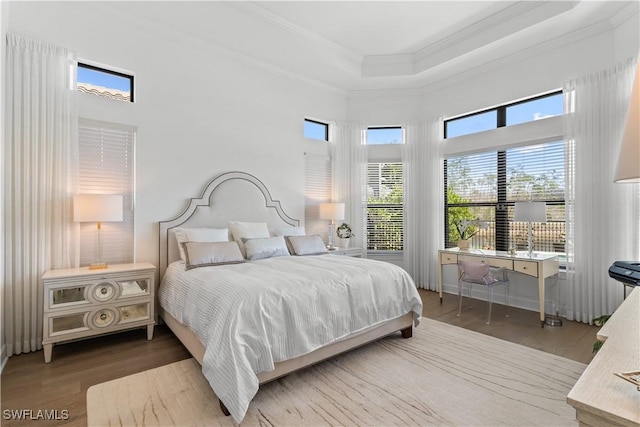 bedroom with a tray ceiling, crown molding, and wood finished floors