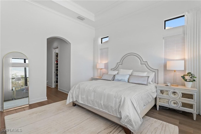 bedroom featuring arched walkways, ornamental molding, wood finished floors, and visible vents