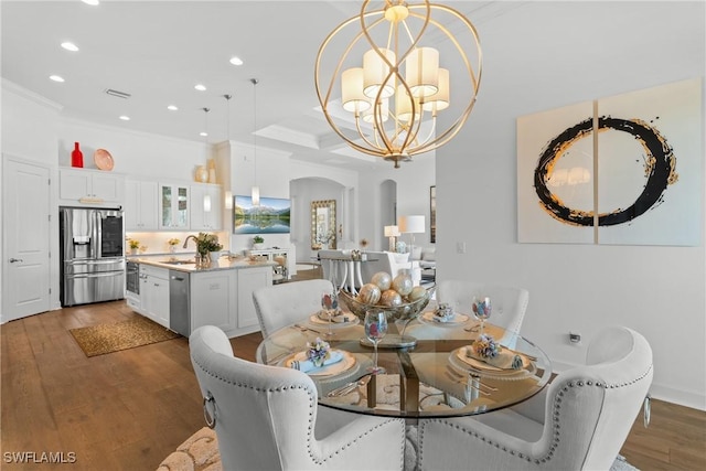 dining room featuring arched walkways, recessed lighting, wood finished floors, ornamental molding, and an inviting chandelier